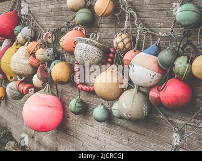 Viele bunte Bojen hängen als Dekoration an einer Holzwand in einem Garten Stockfoto