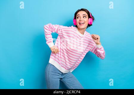 Foto von niedlichen Dame, die im schnurlosen Headset herumtanzen lustig verspielt auf blauem Hintergrund isoliert Stockfoto