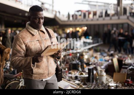 Afroamerikanischer Mann wählt Antiquitäten auf dem Flohmarkt Stockfoto