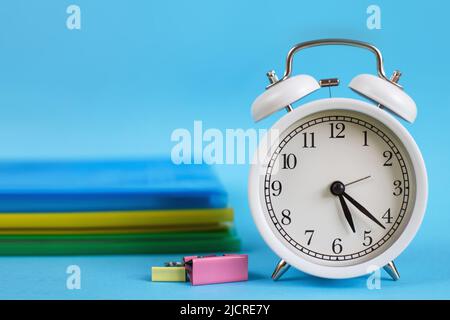 Lehrbücher und Wecker auf blauem Hintergrund. Zurück zur Schule. Bibliothek, Bildung. Konzept Bildung oder Geschäft Stockfoto