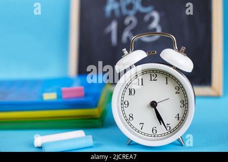 Lehrbücher und Wecker auf blauem Hintergrund. Zurück zur Schule. Bibliothek, Bildung. Konzept Bildung oder Geschäft Stockfoto