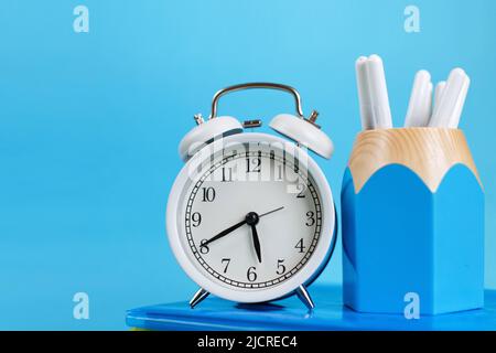 Lehrbücher und Wecker auf blauem Hintergrund. Zurück zur Schule. Bibliothek, Bildung. Konzept Bildung oder Geschäft Stockfoto