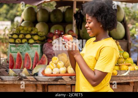 afrikanische Frau, die einen Apfel auf einem Markt hält Stockfoto