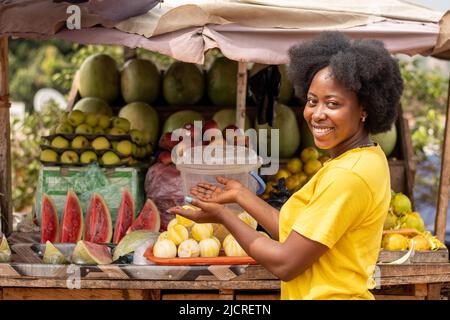 Porträt einer jungen afrikanischen Frau, die Früchte verkauft Stockfoto