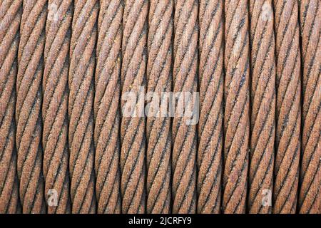 Seilzug aus Stahl. Alte veraltete rostigen Stahl geflochtene Kabel auf Trommel der industriellen Winde selektive fokussieren Makro Nahaufnahme Textur Hintergrund verwundet. Stockfoto