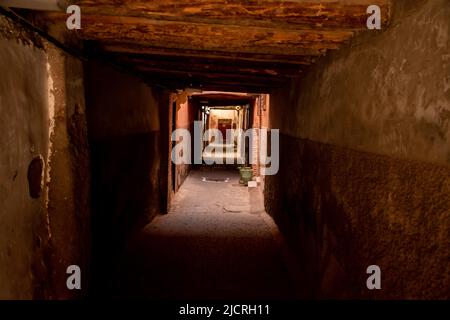 Schatten in einer alten Unterführung auf einer leeren Straße in der historischen Stadtmauer der Medina in Marrakesch, Marokko. Stockfoto