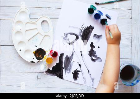 Blick von oben. Kind zeichnet einen Pinsel und malt Draufsicht. Flache Kunstwerkzeuge zum Malen. Stockfoto