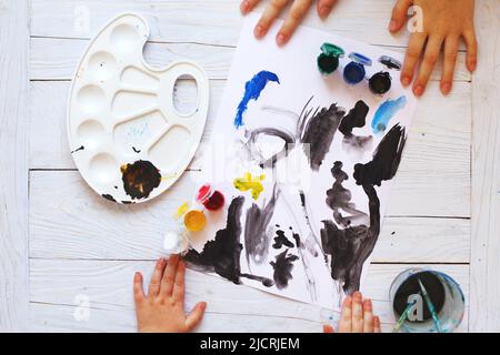 Blick von oben. Kind zeichnet einen Pinsel und malt Draufsicht. Flache Kunstwerkzeuge zum Malen. Stockfoto