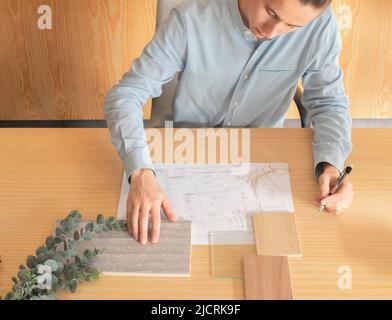 Hände eines anonymen männlichen Innenarchitekten, der in seinem Büro Proben verschiedener Materialien vergleicht Stockfoto