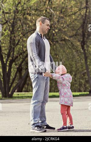 Papa spielt mit seinen Töchtern im Park. Ein Mädchen herumwirbeln. Familie. Stockfoto