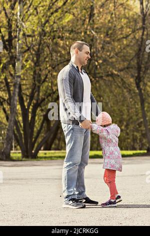 Papa spielt mit seinen Töchtern im Park. Ein Mädchen herumwirbeln. Familie. Stockfoto