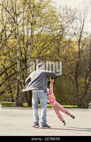 Papa spielt mit seiner Tochter im Hinterhof. Wickelt es um sich herum ab. Familie, Vater spielt mit seiner Tochter am Wochenende. Stockfoto