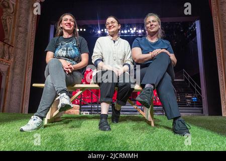 Schwerin, Deutschland. 15.. Juni 2022. Die estnische Komponistin Helena Tulve (m), die Regisseurin Nina Gühlstorff (r) und die Bühnenbildnerin Maroucha Levy (l) sitzen auf dem Kunstrasensaal vor der Bühne des Mecklenburger Staatstheaters. Zur Uraufführung der Naturoper „Wolves“ laufen derzeit Proben. Die Oper beschäftigt sich mit der Rückkehr der grauen Raubtiere in die deutschen Wälder und soll am 24. Juni 2022 uraufgeführt werden. Quelle: Jens Büttner/dpa/Alamy Live News Stockfoto