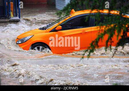 Taxi fährt in schmutzigem Flutwasser auf der Straße Stockfoto