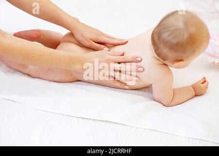 Mutter massiert Baby im Bett zu Hause Stockfoto