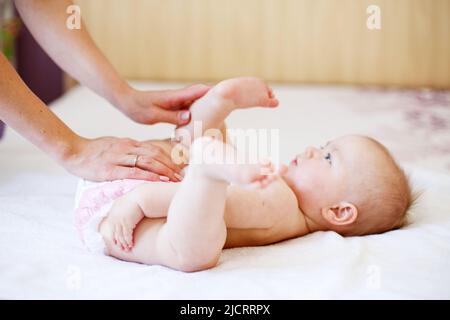 Fürsorgliche junge Mutter, die zu Hause die Windel ihres Babys wechselt Stockfoto