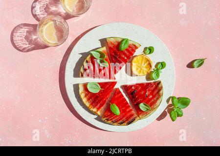 Gegrillte Wassermelonenscheiben mit Zitrone und Basilikum. Sommerdessert Stockfoto