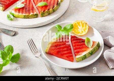 Gegrillte Wassermelonenscheiben mit Zitrone und Basilikum. Sommerdessert Stockfoto