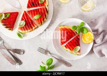 Gegrillte Wassermelonenscheiben mit Zitrone und Basilikum. Sommerdessert Stockfoto