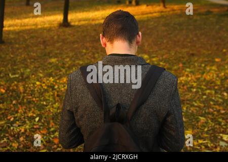 Unschärfe-Effekt bei einem jungen Mann, der das Telefon hält. Mann mit Smartphone im Herbstpark. Textnachrichten eingeben oder soziale Medien auf dem Mobiltelefon lesen. Herbsthintergrund Stockfoto