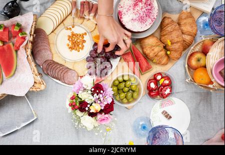 Blick vom Himmel auf Charcuterie Picknick mit Blumen an einem Sommertag Stockfoto