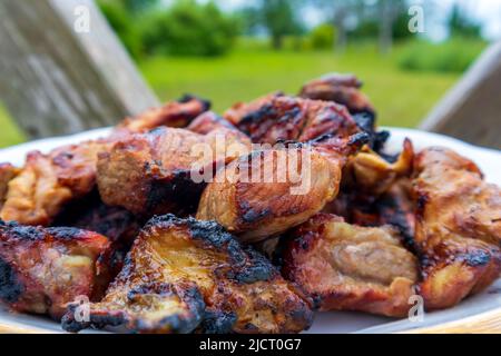 Gekochtes Steak auf einem Grill mit einer roten Tomate Stockfoto