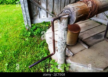 Ein alter Brunnen in einem europäischen Dorf mit einem Metalleimer Stockfoto