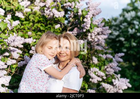 Ein zartes Porträt einer Mutter und Tochter am Flieder. Stockfoto
