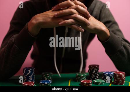 Unglücklicher junger Mann, der sich traurig, verzweifelt und gestresst fühlt, nachdem er sein Geld beim Poker und Blackjack in einem nächtlichen Casino verloren hat Stockfoto