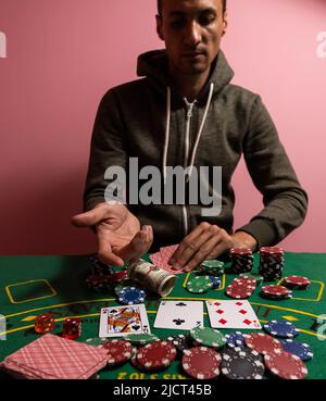 Unglücklicher junger Mann, der sich traurig, verzweifelt und gestresst fühlt, nachdem er sein Geld beim Poker und Blackjack in einem nächtlichen Casino verloren hat Stockfoto