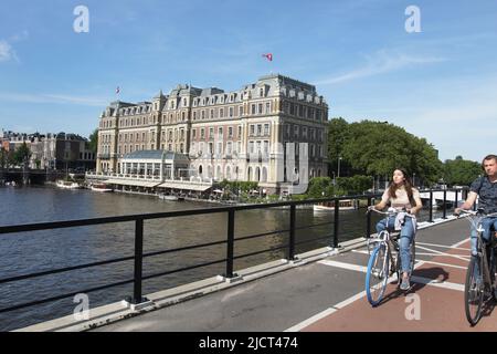 Amsterdam, Niederlande. 15.. Juni 2022. Mitglieder der Öffentlichkeit fahren mit dem Fahrrad über die Brücke in der Nähe des Amstel Hotels, wo Mick Jagger nach der Untersuchung auf Coronavirus-Krankheit (Covid-19) am vergangenen Dienstag, dem 15. Juni 2022, in Amsterdam, Niederlande, in Quarantäne ist. (Foto von Paulo Amorim/Sipa USA) Quelle: SIPA USA/Alamy Live News Stockfoto