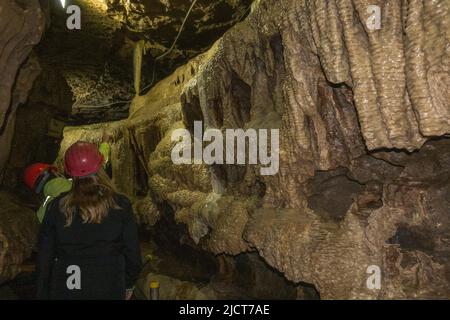 Besucher in Hartmützen in den atemberaubenden White Scar Caves in Ingleton, North Yorkshire, England. Stockfoto