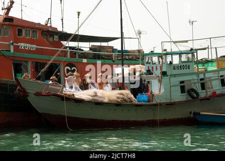 Fischer hüten ihre Netze auf einem Boot im Hafen von Aberdeen, Hongkong. Stockfoto