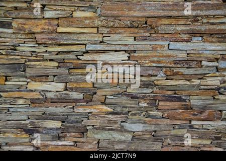 Steinwand aus mehrfarbigem geschichtetem Natursandstein Stockfoto