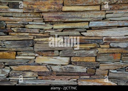 Steinwand aus mehrfarbigem geschichtetem Natursandstein Stockfoto