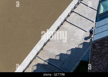 Eine Luftaufnahme eines Einzelmenschen, der am Ufer des Flusses Lea in London E14 sitzt. Stockfoto