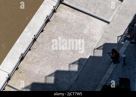 Eine Luftaufnahme eines Einzelmenschen, der am Ufer des Flusses Lea in London E14 sitzt. Stockfoto