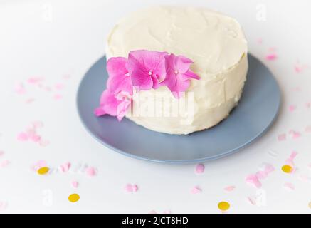 Sehr schöne kleine weiße Bento-Torte, dekoriert mit frischen Blüten von rosa Hortensien. Urlaub und Spaß Konzept Stockfoto