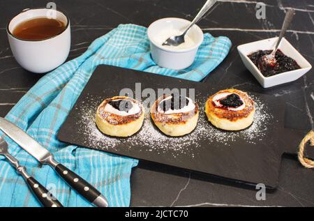 Süße Käsepfannkuchen auf dem Teller servierten Erdbeeren. Syrniki, Ricotta-Krapfen, Quark-Krapfen. Stockfoto