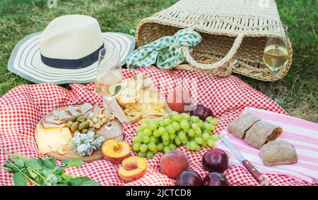 Sommerpicknick im Park auf dem Rasen. Wein, Obst und Croissants. Stockfoto