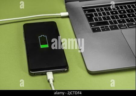 Smartphone Laden des Akkus vom Laptop mithilfe der Ladetechnologie. Stockfoto