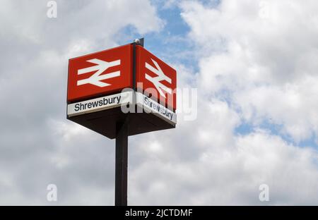 Ein Schild für den Bahnhof Shrewsbury mit dem legendären rot-weißen British Rail-Logo und isoliert gegen den Himmel. Reise- oder Tourismuskonzept. Stockfoto