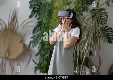 Beeindruckte junge Frau, die sich aufgeregt fühlte, als sie das vr-Headset im Garten testet Stockfoto