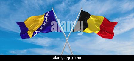 Zwei gekreuzte Flaggen Bosnien und Herzegowina und Belgien winken im Wind bei bewölktem Himmel. Konzept der Beziehung, des Dialogs, des Reisens zwischen zwei Ländern. Stockfoto