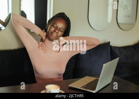 Ängstlich und müde gemischte Rasse Geschäftsfrau, Hals halten, Schmerzen fühlen, mit Laptop im Café. Sitzende Arbeit, falsche Haltung Stockfoto