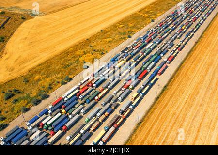 In einem blockierten ukrainischen Hafen steht eine riesige Schlange von Lastwagen, die mit Getreidepflanzen beladen sind. Humanitäre Krise durch den Krieg. Stockfoto