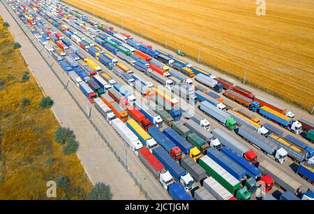 In einem blockierten ukrainischen Hafen steht eine riesige Schlange von Lastwagen, die mit Getreidepflanzen beladen sind. Humanitäre Krise durch den Krieg. Stockfoto