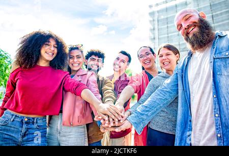 Portrait von glücklichen vielfältigen große Gruppe von multikulturellen Freunden, die ihre Hände halten, die fünf hoch stapeln, die sie im Freien zusammenstapeln Stockfoto