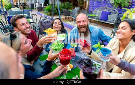 Fröhliche, vielfältige, große Gruppe multikultureller Freunde, die mit wunderschönen Gourmet-Cocktailgläsern im Barrestaurant feiern Stockfoto
