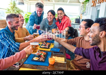 Multiethnische große Gruppe von Freunden sitzen am Tisch in einer Bar Restaurant mit Brunch. Diverse Menschen Sellerie salzigen Frühstück zusammen genießen Stockfoto